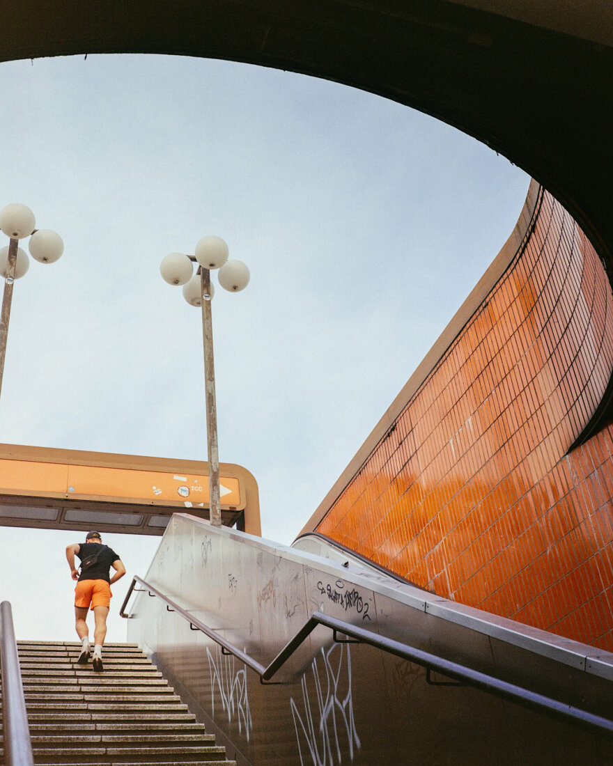 a man in orange shorts walking up the stairs from underpass